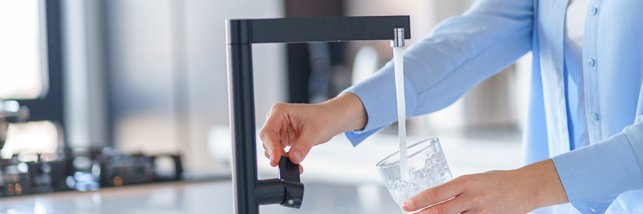 Frau holt sich Wasser aus dem Wasserhahn